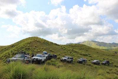 A group of friends enjoying an off-road trip, smiling beside their vehicles under a wide blue sky.