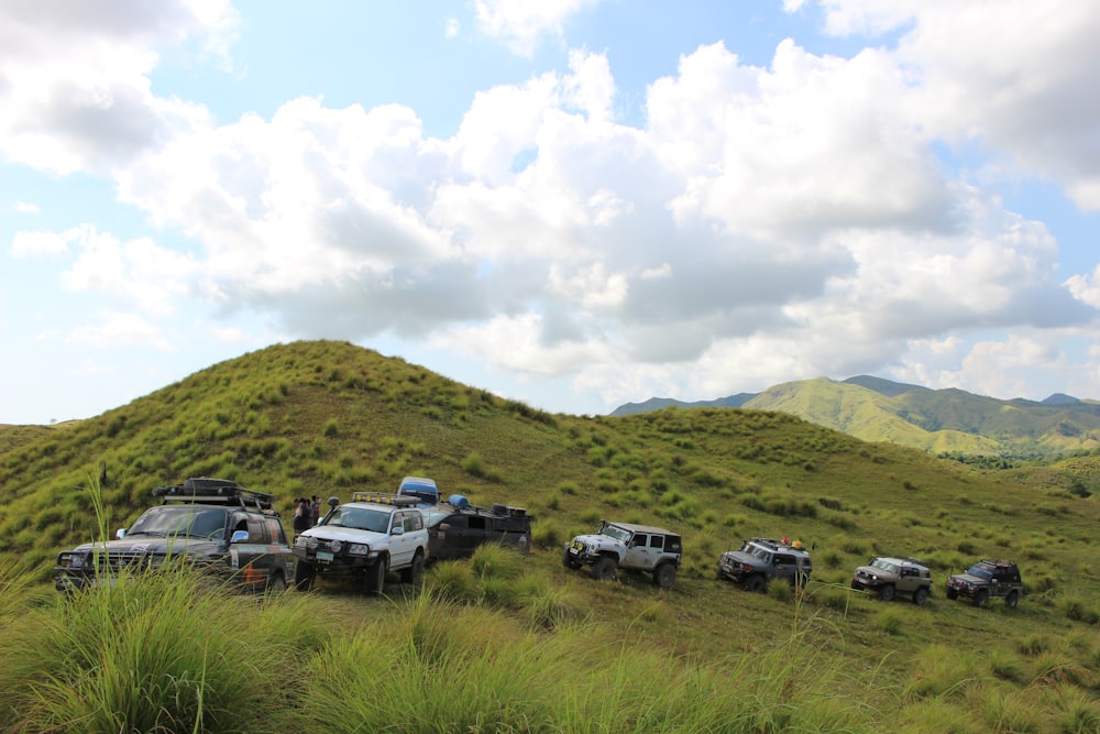 a group of jeeps parked on top of a lush green hillside