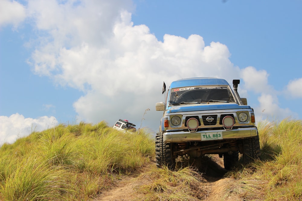 a blue truck driving down a dirt road