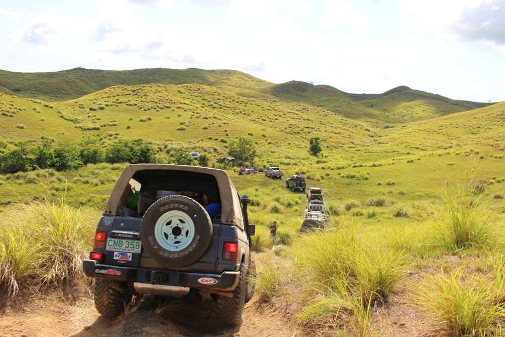 a jeep driving down a dirt road in the middle of a field