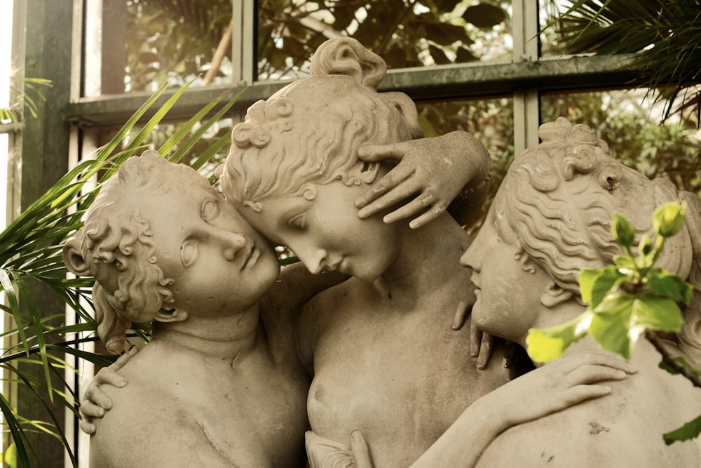 a statue of three cherubs in front of a window