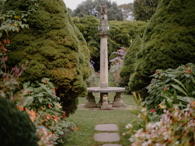 Wide shot of a serene garden featuring several Verdeviva sculptures nestled among blooming flowers.
