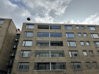 Street view of a multifamily building with brick facade and large windows.