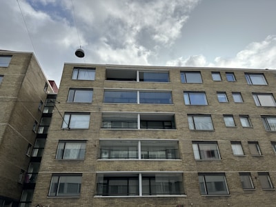 Street view of a multifamily building with brick facade and large windows.