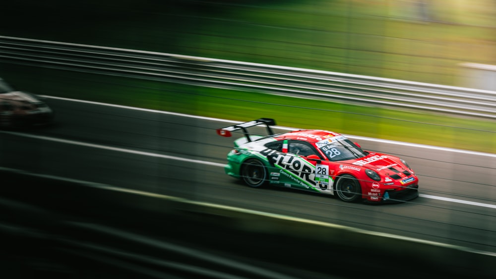 a red and green car driving down a race track