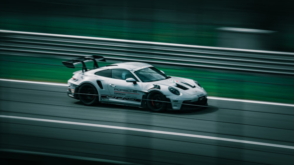 a white sports car driving down a race track