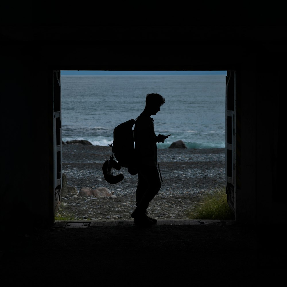 a silhouette of a person holding a backpack