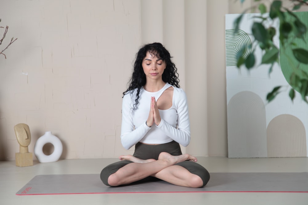 a woman sitting in a yoga position with her eyes closed