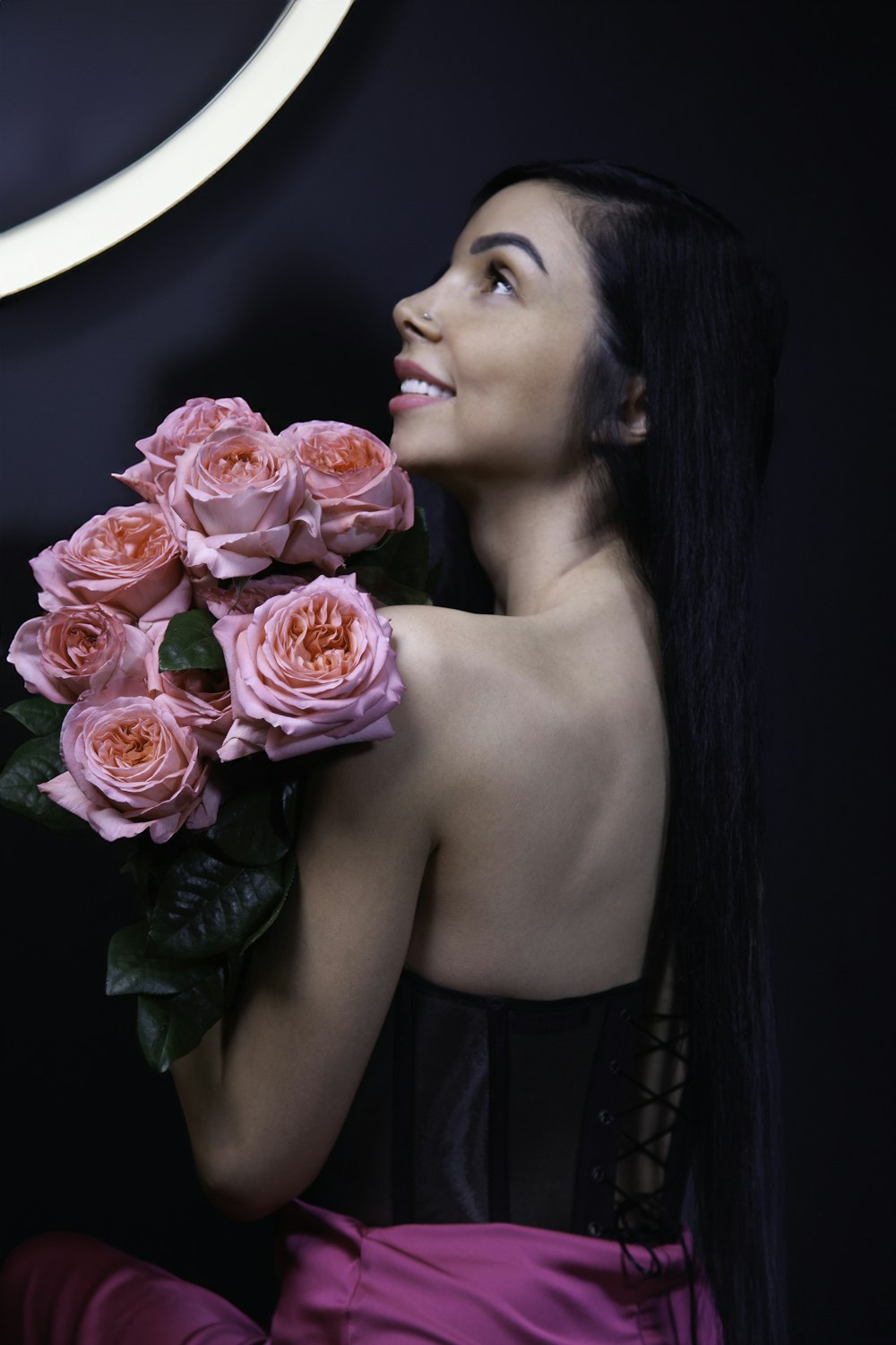 a woman holding a bunch of pink roses