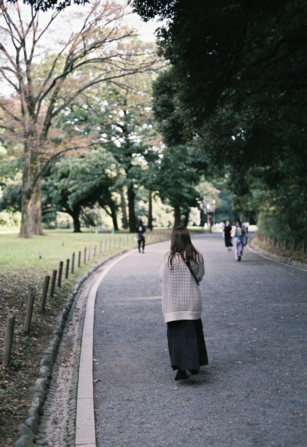 a woman walking down a road in a park