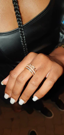 Glossy black coffin-shaped nails with subtle diamond detailing, styled with gold rings.