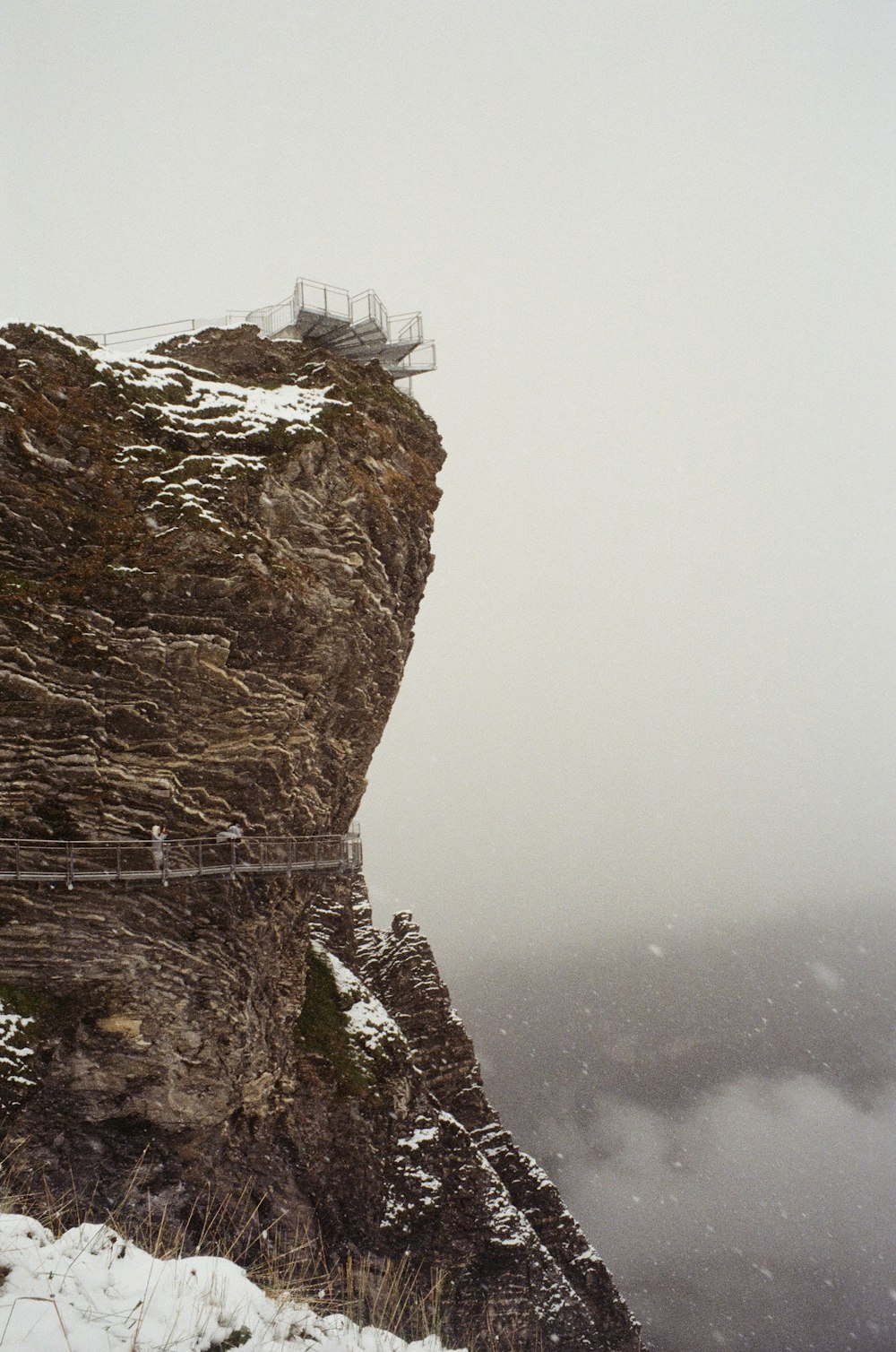 a couple of people walking across a bridge on top of a mountain