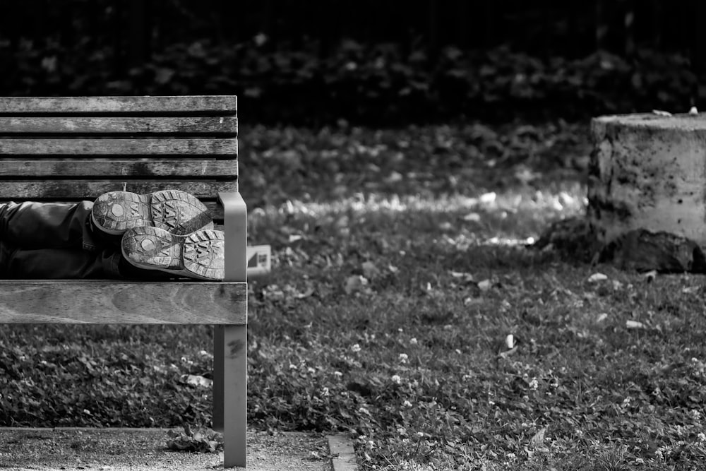 a black and white photo of a person sleeping on a bench