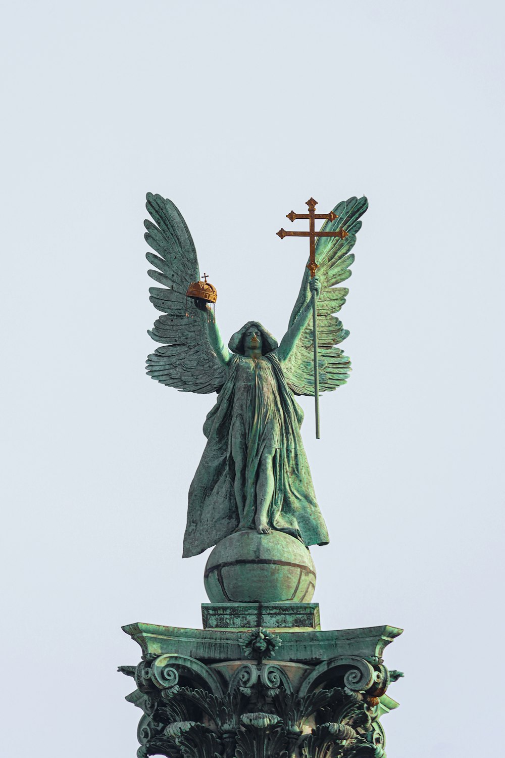 a statue of an angel holding a cross on top of a building