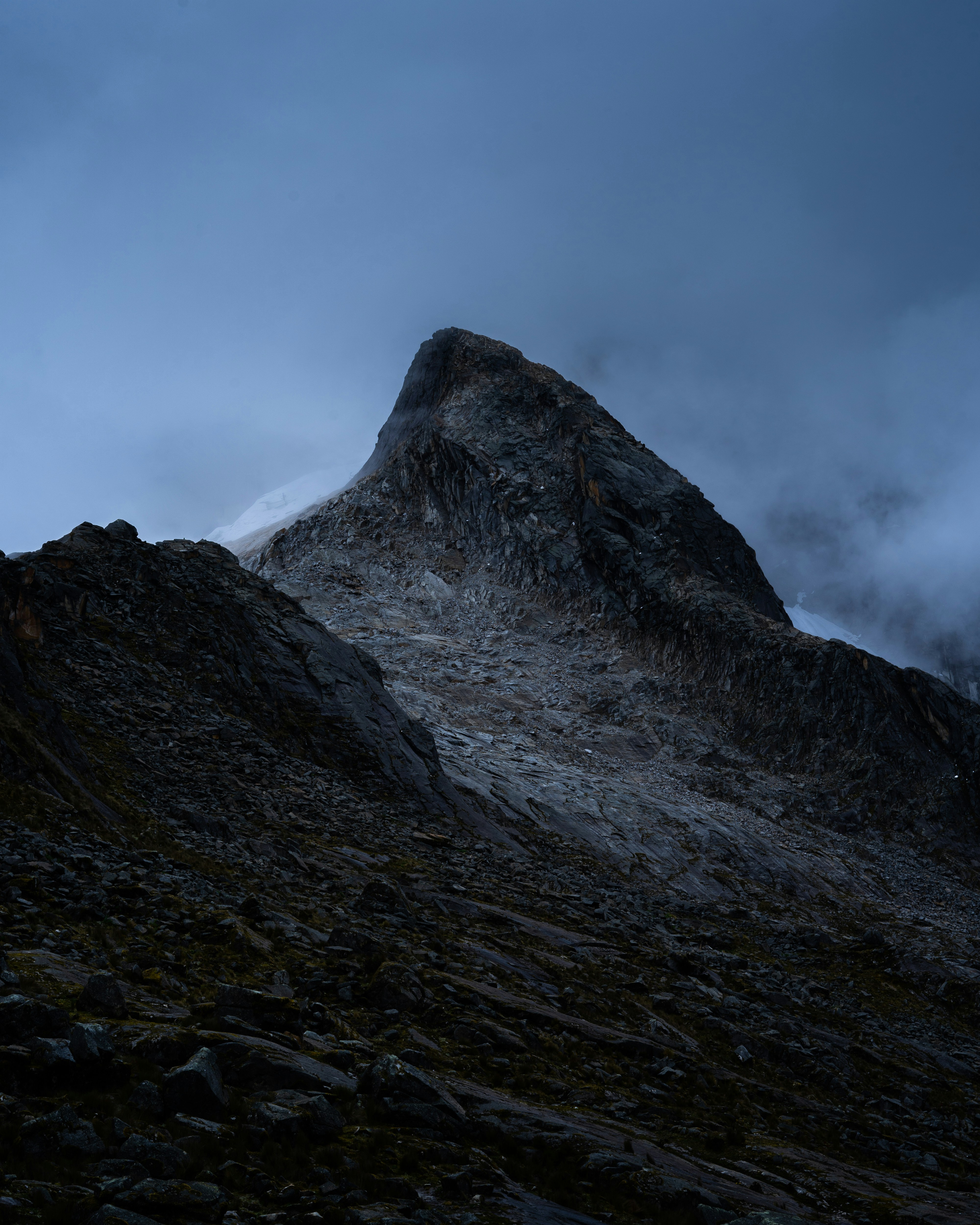 Solar panel on rocky mountain summit under dramatic dark storm clouds, rugged terrain, moody atmosphere