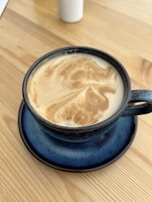 Close-up of a steaming cup of coffee on a white table with a hint of blue decor.