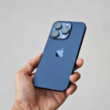Close-up of a hand holding a latest model smartphone with a glowing blue nexstar logo.