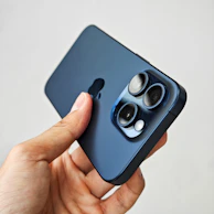A hand holding a smartphone with a clear view of the camera lens and sleek design.