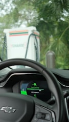 Electric vehicle dashboard showing charging progress with vibrant green energy indicators.