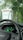 A car interior view focuses on the dashboard display showing an electric vehicle fast charging status at 80% completion with 40 minutes remaining. The steering wheel features a Chevrolet logo. Outside the windshield, a charging station is visible amidst a lush, green, and slightly rainy environment.