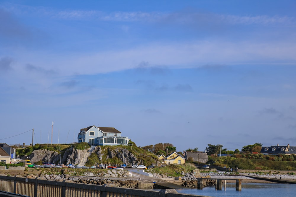 a house sitting on top of a hill next to a body of water