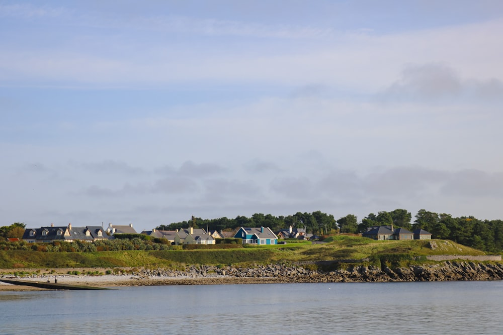 a row of houses sitting on top of a hill next to a body of water