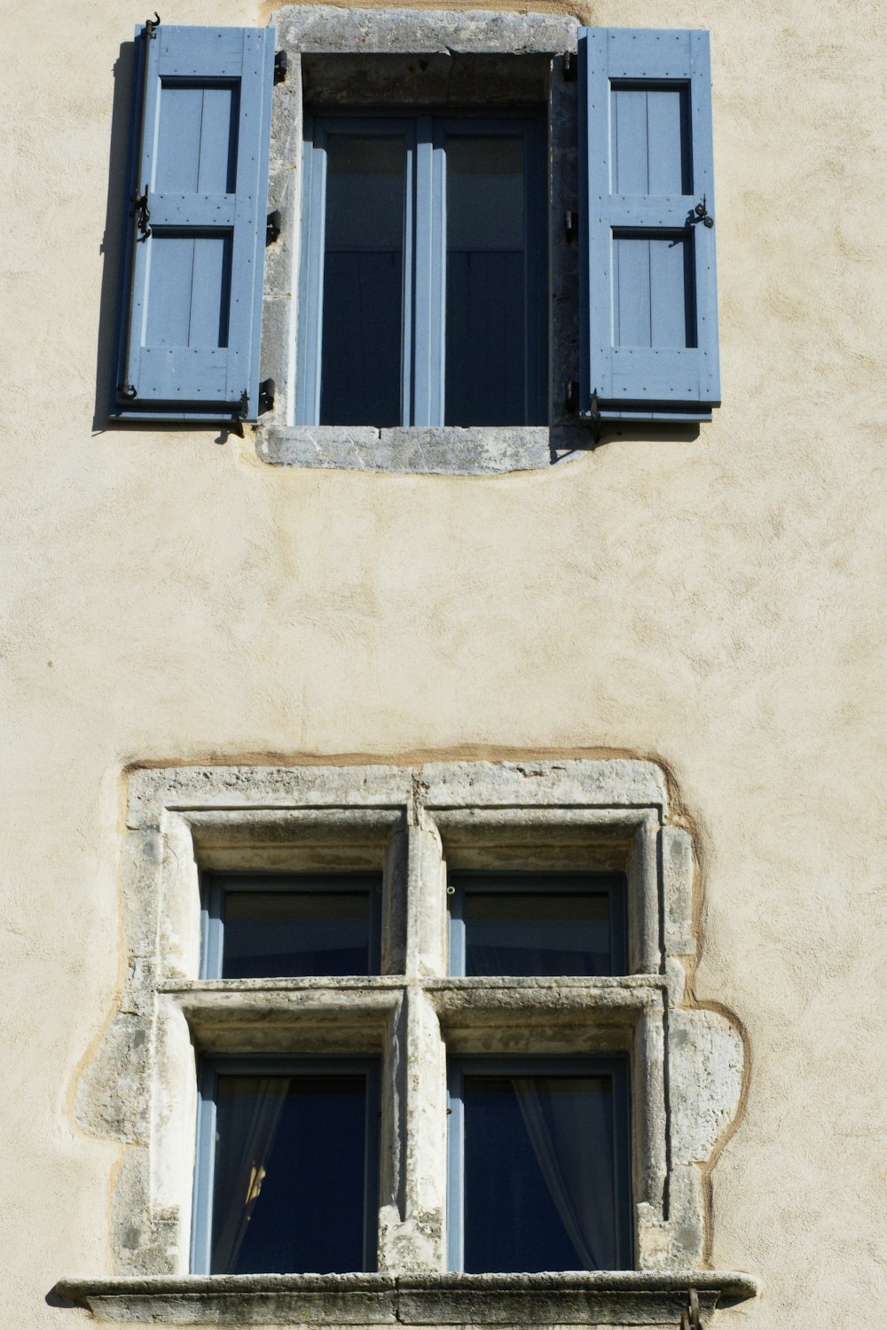 two windows with blue shutters on a building