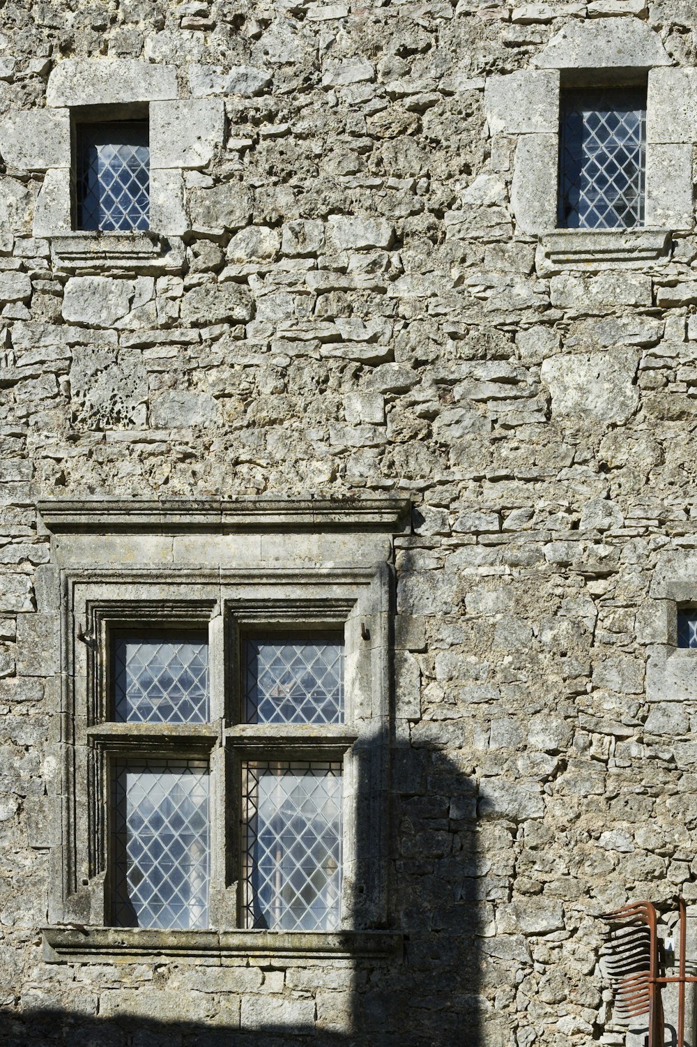 a stone building with two windows and a chair in front of it