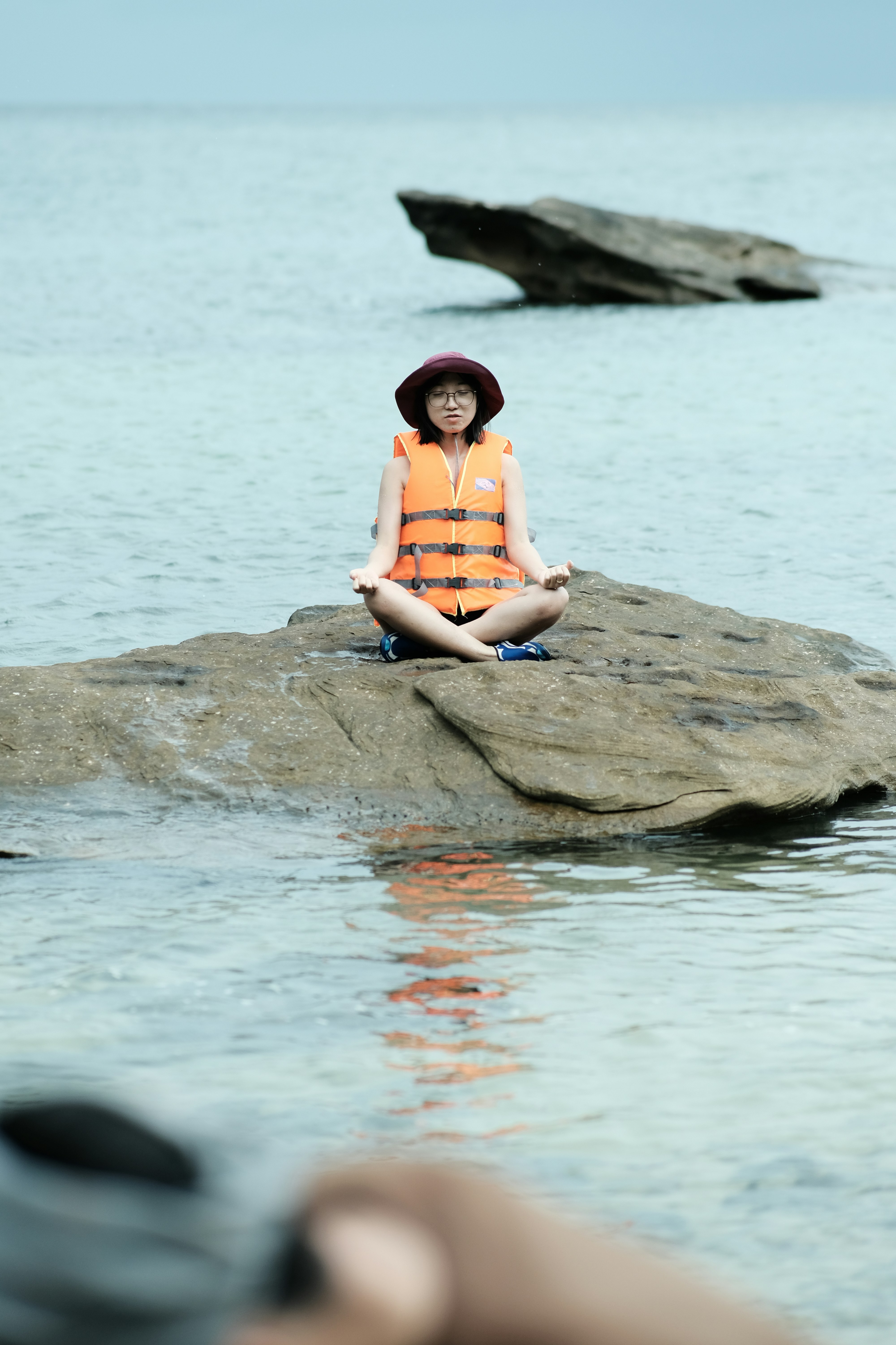A person sitting on a rock in the water