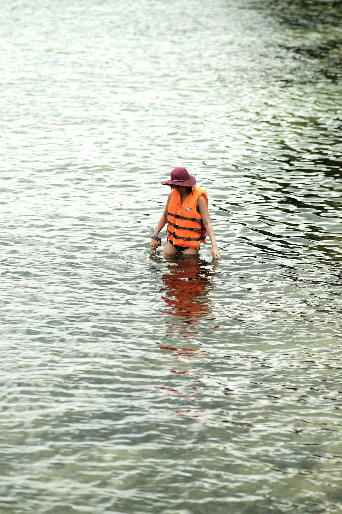 Person wearing a bright life jacket while standing in open water