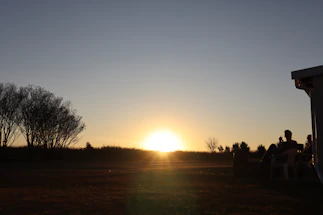 A serene landscape with a peaceful sunset over a community gathering.