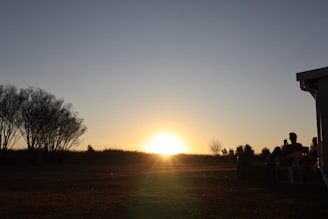 A warm sunset over a serene natural landscape with travelers enjoying a peaceful moment outdoors.