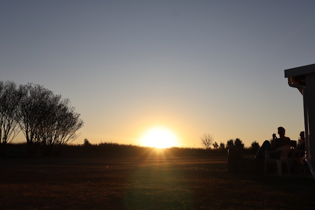 A warm sunset over a serene natural landscape with travelers enjoying a peaceful moment outdoors.