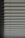 Horizontal window blinds casting layered shadows with alternating light and dark sections, forming a pattern on the surface.