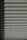 Horizontal window blinds casting layered shadows with alternating light and dark sections, forming a pattern on the surface.
