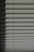 Horizontal window blinds casting layered shadows with alternating light and dark sections, forming a pattern on the surface.