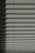 Horizontal window blinds casting layered shadows with alternating light and dark sections, forming a pattern on the surface.