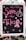 A blackboard with pink chalk writing features the phrase 'Save the Tatas' accompanied by decorative elements like hearts and a ribbon symbol often associated with breast cancer awareness. The board is framed in white and surrounded by a few blurred flowers at the bottom.