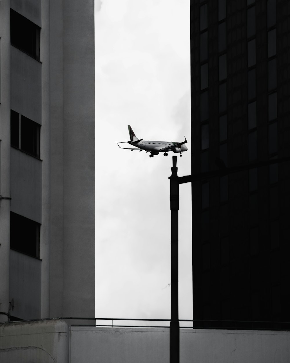 an airplane is flying over a building and a street light