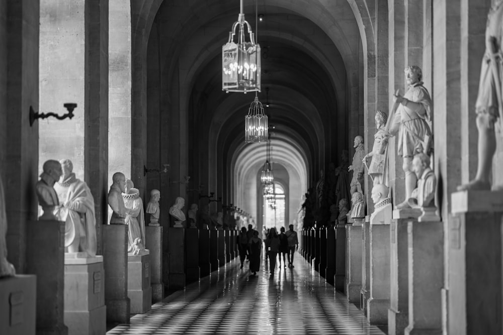 a black and white photo of a hallway with statues