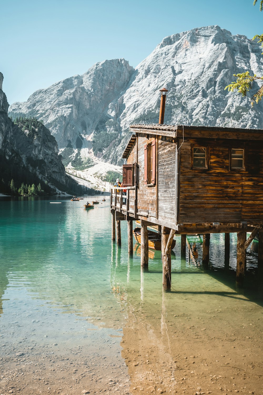 a wooden house sitting on top of a lake next to a mountain