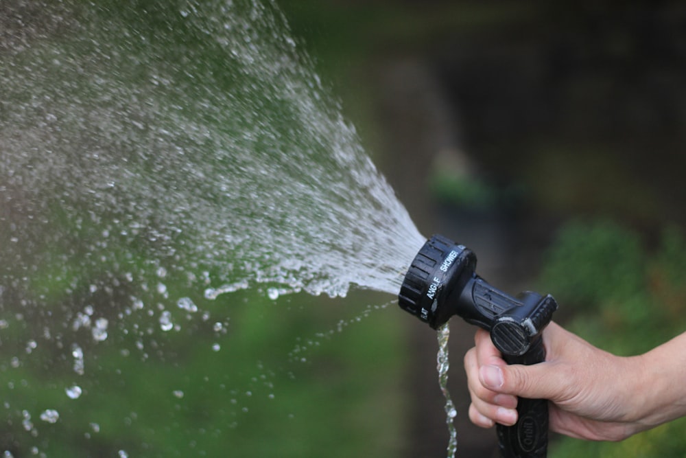 a hand holding a water hose spraying water