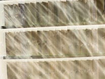 Sunlight streams through wooden planks, casting beams of light and creating a pattern of light and shadow. The wood appears weathered, with visible grain and knots.