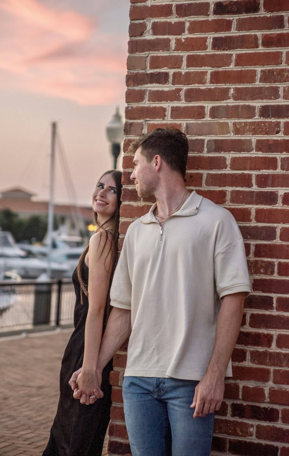 a man and a woman standing next to a brick wall