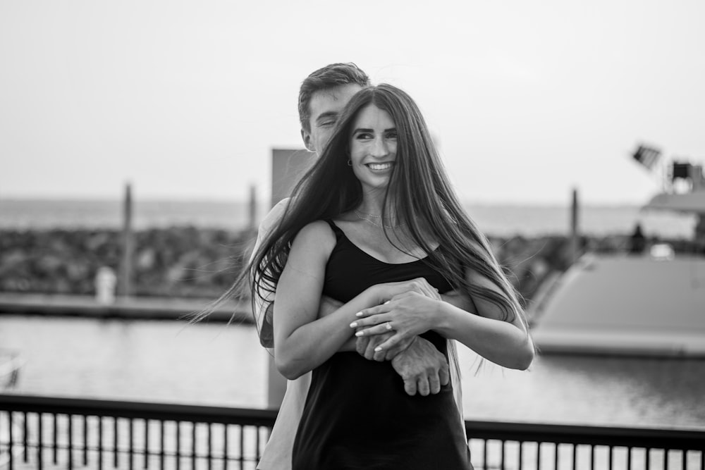 a man holding a woman in his arms in front of a body of water