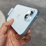 Hands holding a cutting-edge gadget with a futuristic design under soft blue lighting.