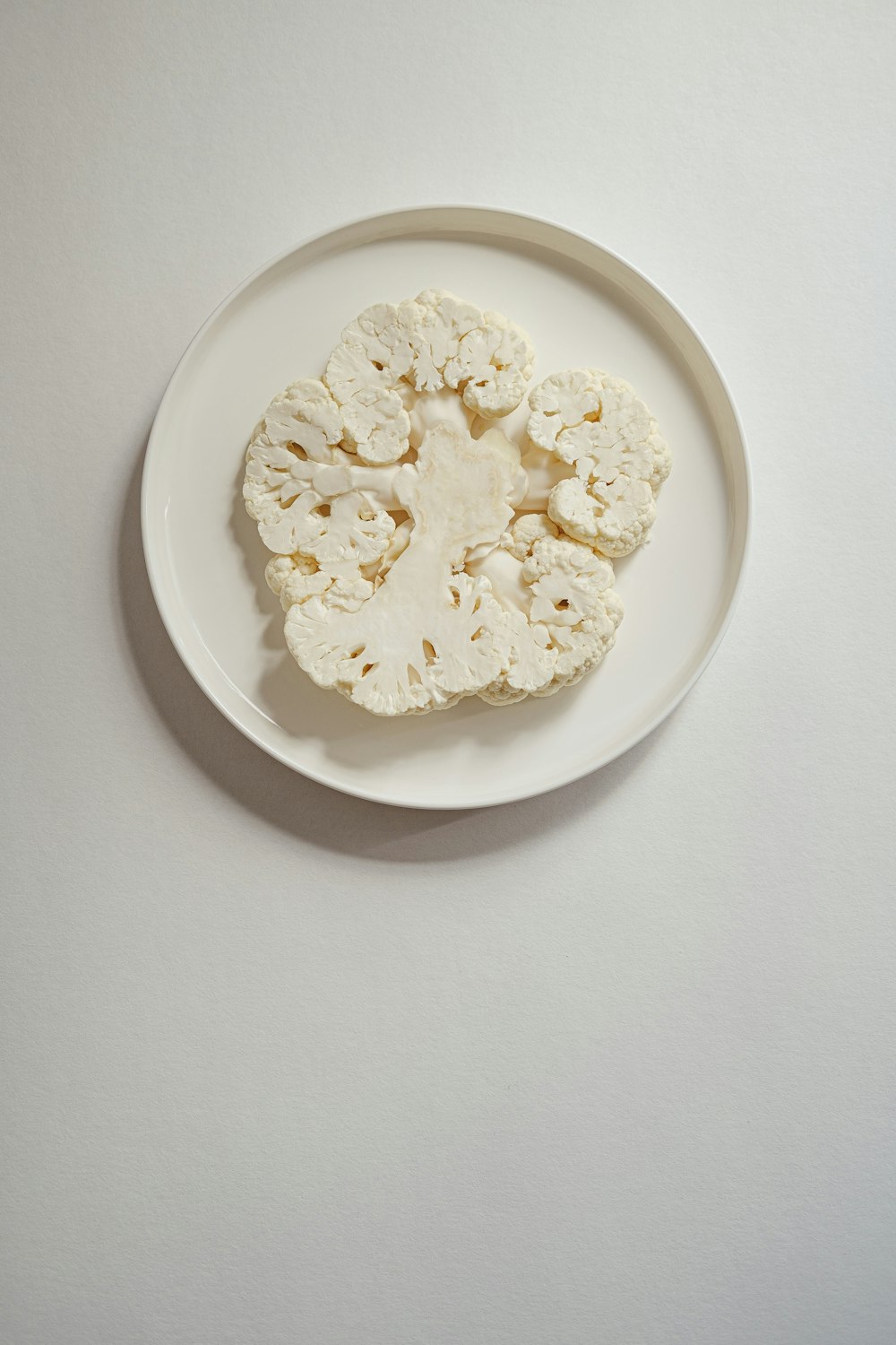 a white plate with a piece of cauliflower on it