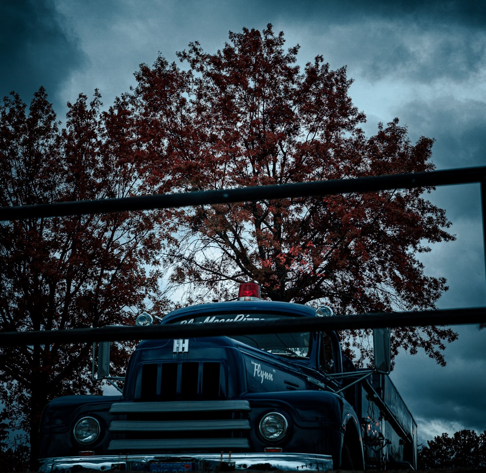 an old truck is parked in front of a tree