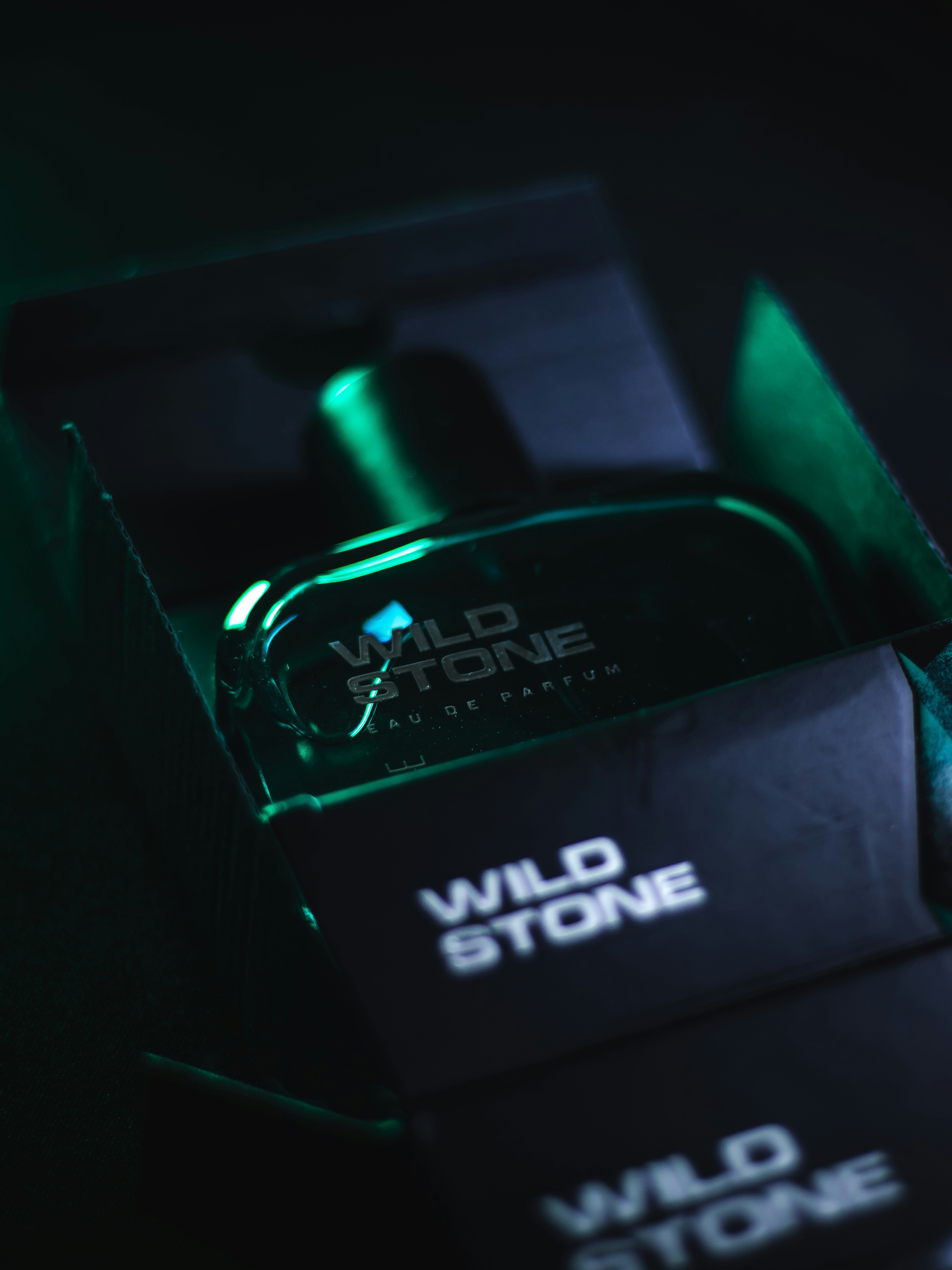 Sleek masculine perfume bottle on dark concrete surface, industrial moody lighting, strong shadows, premium product photography