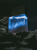 a bottle of denver cologne sitting on a rock